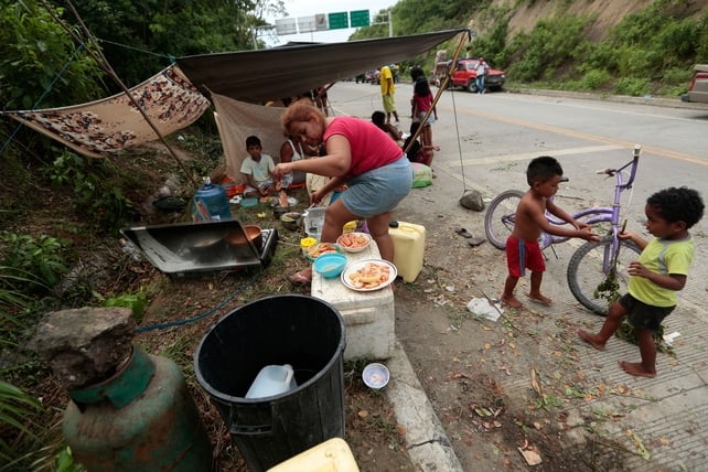 A woman prepares a meal by the side of the road in Chone