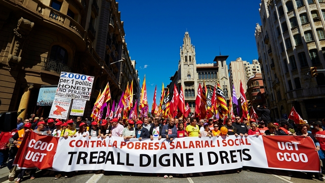 Participants march behind a banner reading 'Against Labour and Social Poverty: For a Decent Job and Rights' in Barcelona, Spain