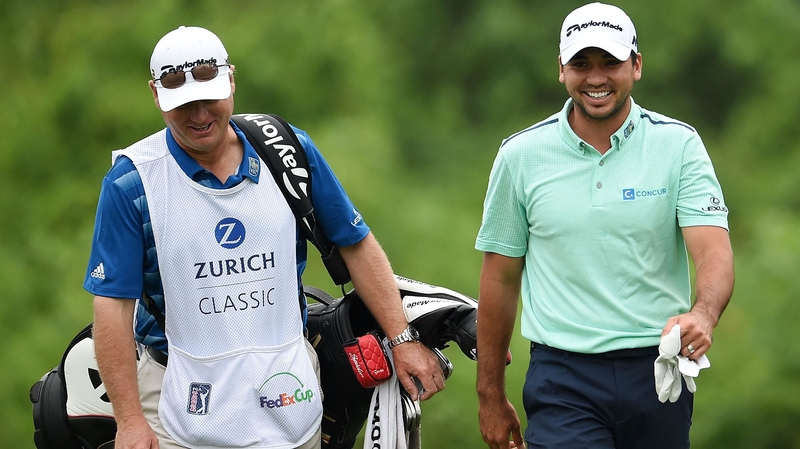 Jason Day (R) walks down the second fairway with his caddie