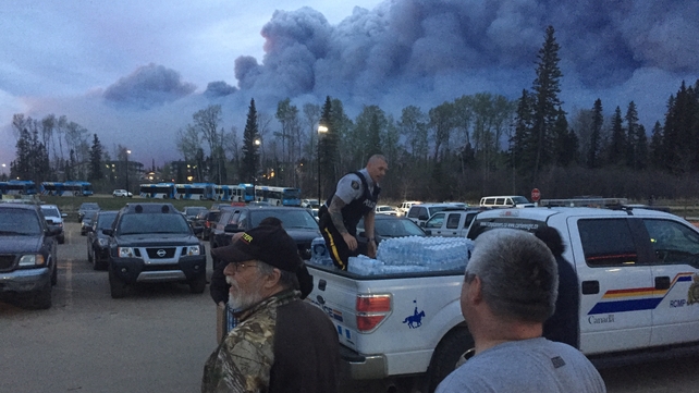 Evacuated residents look on as smoke clouds move in the direction of an evacuation centre set up in the neighbouring area of Anzac