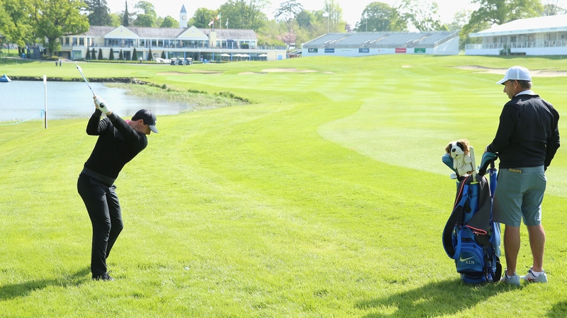Rory McIlroy plays his second shot on the 18th hole as his caddie JP Fitzgerald looks on during practice