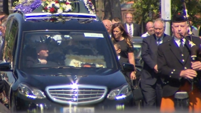 The funeral procession was led by a lone bagpiper and the coffin was accompanied by a large crowd of mourners