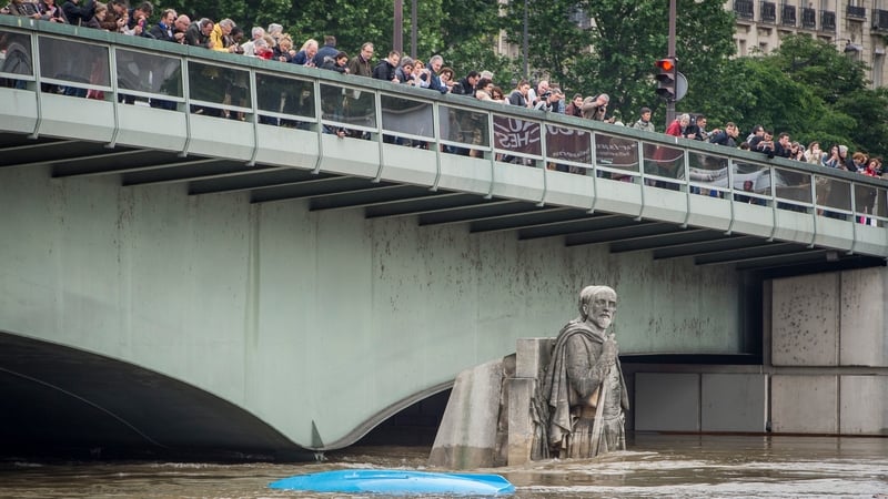 People watch the water levels of the Seine from Pont de l'Alma bridge with the partially submerged statue 'Le Zouave'