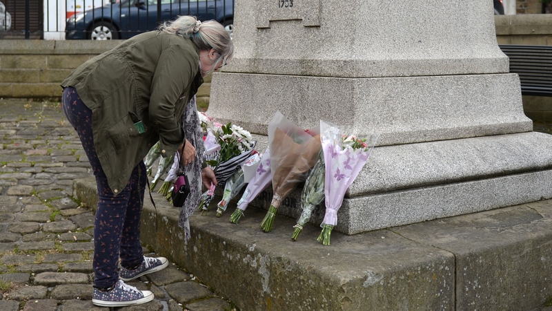 A woman lays flowers at a statue near the scene where Jo Cox was attacked