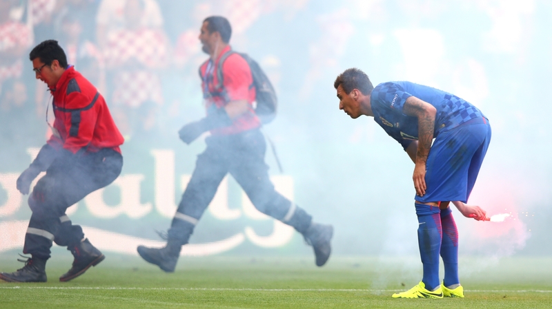 Croatian players and stewards remove flares from the field