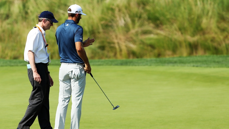 Dustin Johnson speaks to an official on the fifth green
