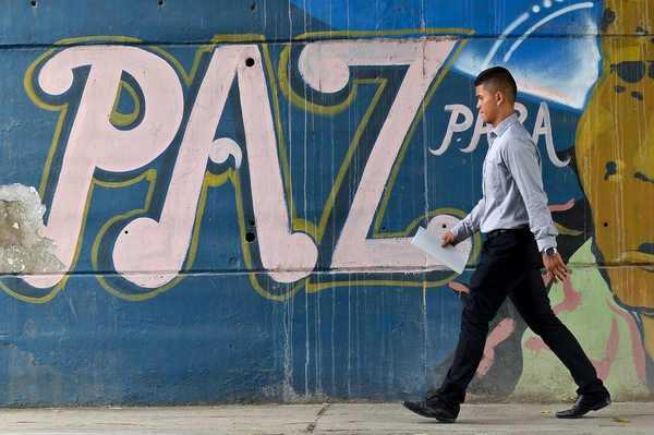 A man passes by a graffiti reading 'Peace for the people' in Cali, Colombia