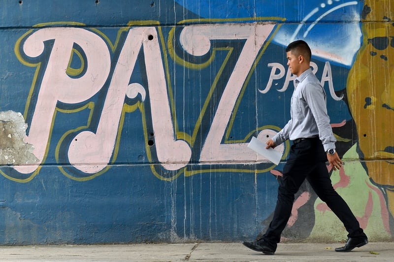 A man passes by a graffiti reading 'Peace for the people' in Cali, Colombia