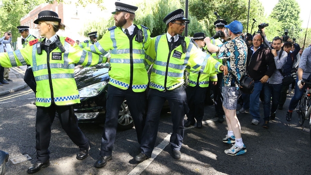 Police officers link arms in front of a car carrying Boris Johnson from his home in north London, after David Cameron announced he will quit as prime minister by October