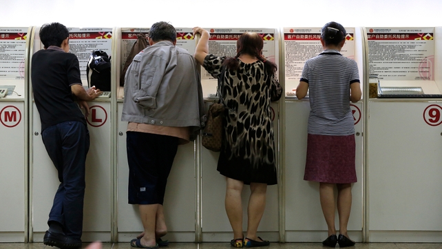 Investors look at computer screens showing stock market movements at a securities brokerage house in Beijing, China