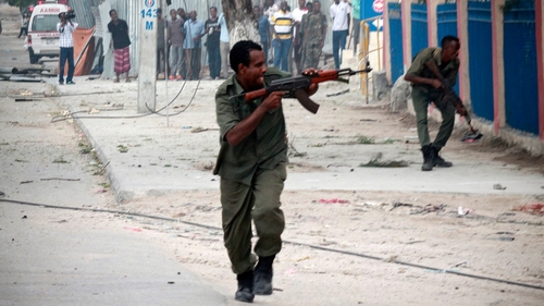 Somali security offciers take positions as they fight attackers in front of the hotel in Mogadishu, Somalia