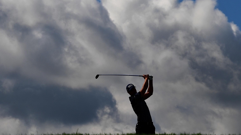 Henrik Stenson of Sweden hits an approach shot as dark clouds circle