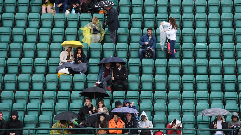Spectators at Wimbledon take cover from the rain