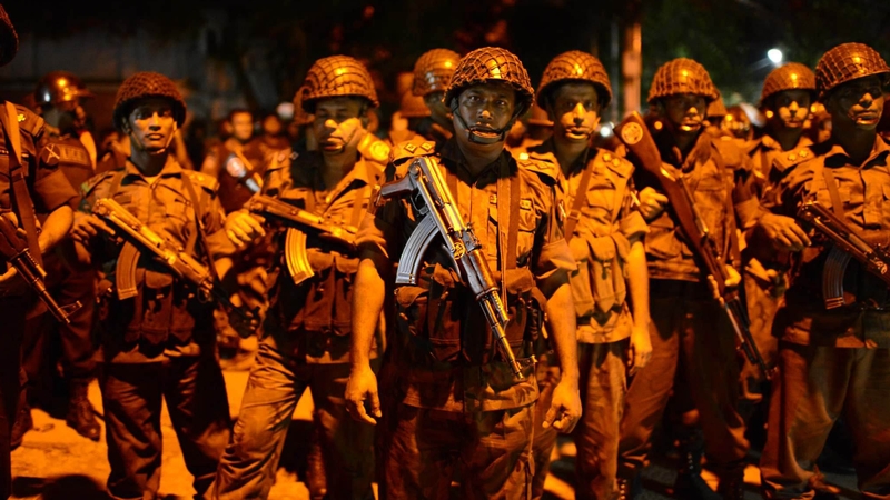 Bangladeshi security stand guard near the restaurant that has been attacked by gunmen
