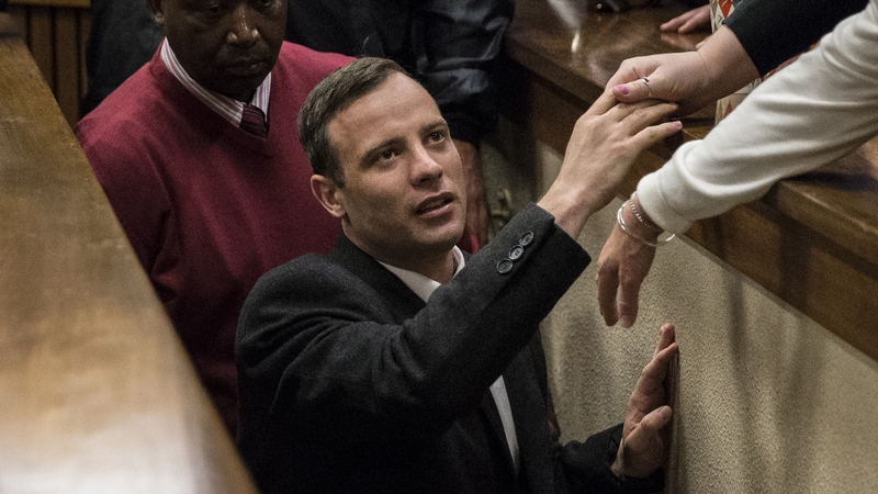 Oscar Pistorius holds the hand of a relative as he was taken out of court to begin serving his term