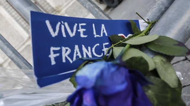 A floral tribute and message reading 'Vive la France' is left at a fence erected outside the French Embassy in Rome