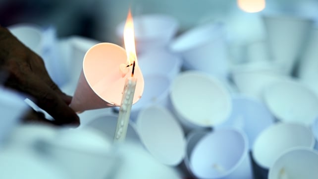 A man lights a candle during a candlelight vigil at the Alliance Francaise in Bangkok