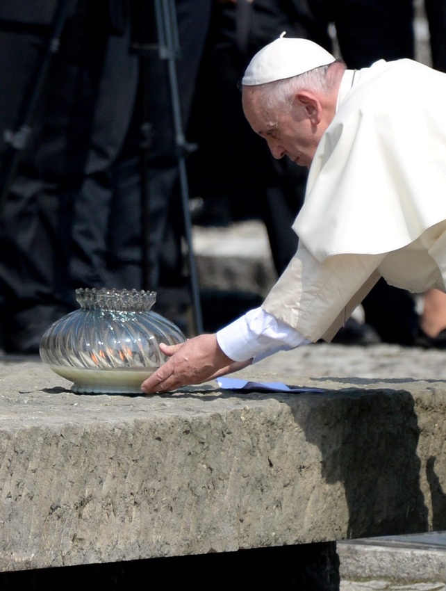 Francis lights a candle at the International Monument to the Victims of Fascism