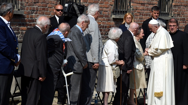Francis meets with former Auschwitz prisoners in a yard area next to the Death Wall