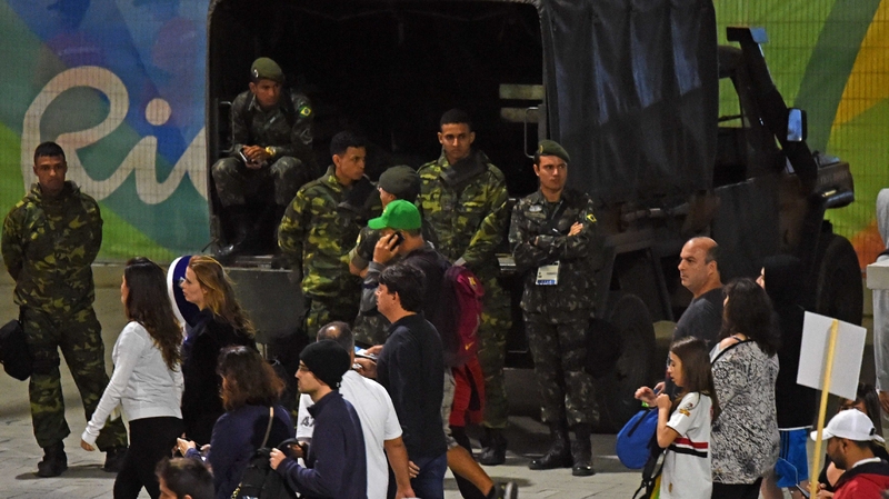 Soldiers watch on as spectators walk outside the Carioca Arena 1 in Rio