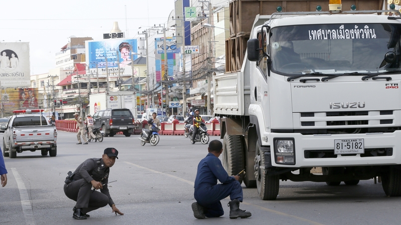 Police officers take cover after a bomb exploded at the city clock tower in the centre of Hua Hin