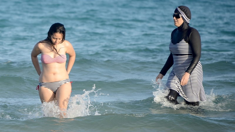 Two Tunisian women swim at a beach near Tunis, one wearing a burkini