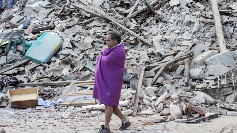 Fear ag siúl trína bhfuil fágtha de cheann de na bailte a buaileadh le crith talúin san Iodáil aréir. Maraíodh 73 ar a laghad agus iarrachtaí tarrthála faoi lán tseoil