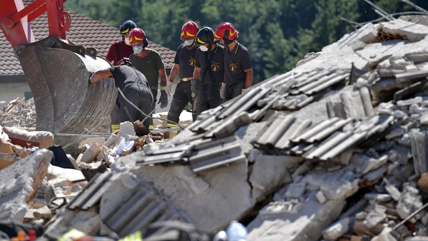 Rescue workers search through the rubble of a destroyed building for survivors in Amatrice
