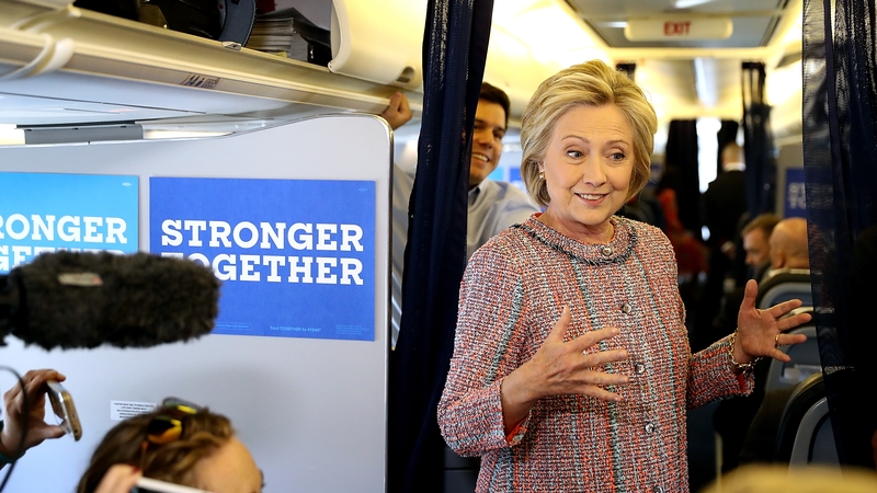 Hillary Clinton speaks to members of the travelling press aboard her campaign plane
