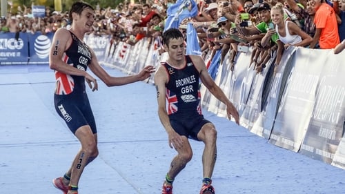 Alistair Brownlee (L) helps his brother Jonny before crossing the line in second and third place during the ITU World Triathlon Championships