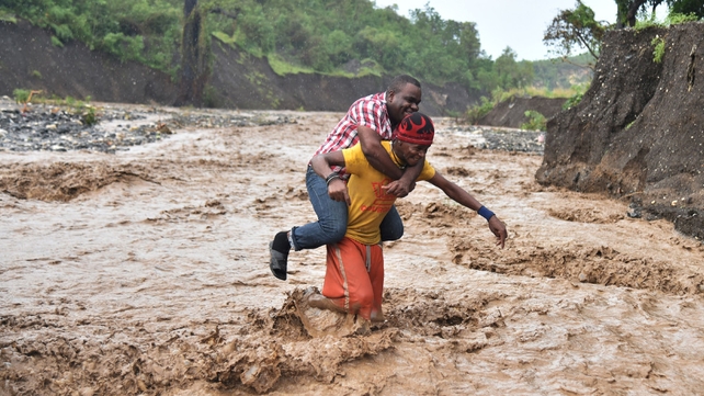 A man is carried across the river La Digue in Petit Goave where the bridge collapsed during the hurricane rains southwest of Port-au-Prince, Haiti