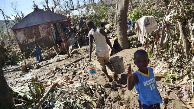 A young man carries water to remove the mud of his house destroyed by Hurricane Matthew in Jeremie