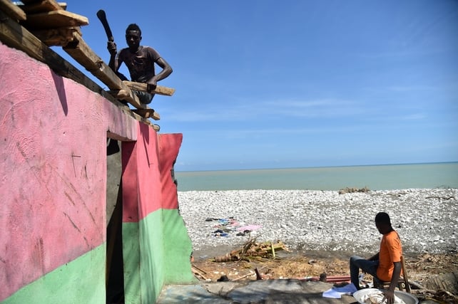 Members of a family repair their home damaged by Hurricane Matthew in Gomier