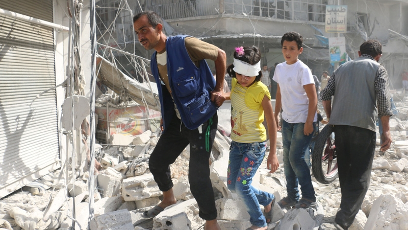 Syrians walk over rubble following air strikes on the rebel-held Fardous neighbourhood of Aleppo