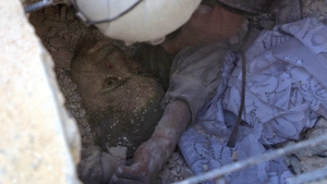 Jameel Mustafa Habboush, a 13-year-old Syrian boy, looks at a member of the civil defence volunteers as they rescue him from under the rubble of a building following Russian air strikes