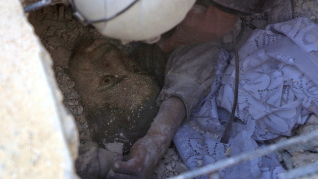 Jameel Mustafa Habboush, a 13-year-old Syrian boy, looks at a member of the civil defence volunteers as they rescue him from under the rubble of a building following Russian air strikes