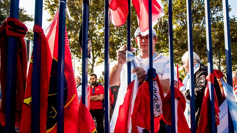 A Racing Metro Fan ties a scarf to the gates of Stade Yves Du Manoir as a tribute to Anthony Foley