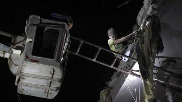 A member of the Syrian Civil Defence rescue Maarouf, a 12-year-old Syrian boy, from the rubble of a building following a reported air strike in Aleppo yesterday