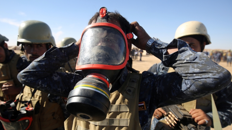 An Iraqi policeman tries on a gas mask outside Mosul