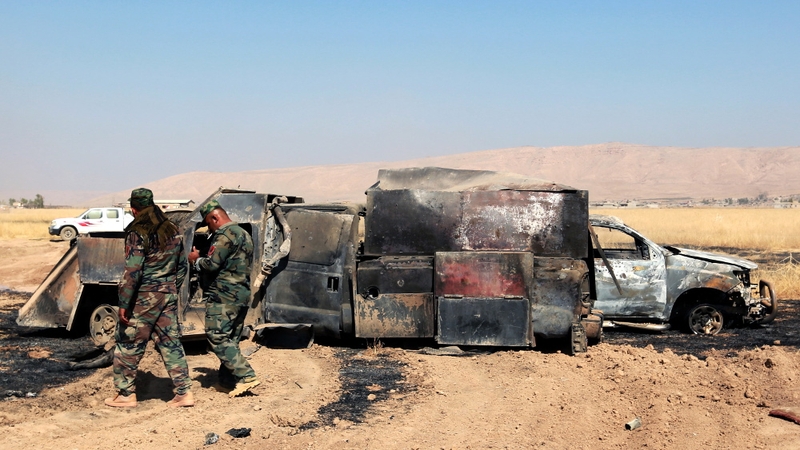Soldiers inspect a burnt truck used by militants to liberate several villages from the control of IS, east of Mosul