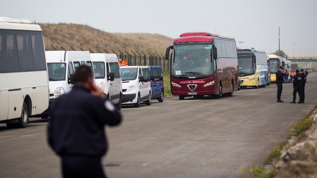 Buses to take migrants to refugee centres across France queue outside a reception point