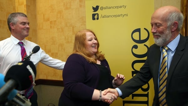 Naomi Long shakes hands with outgoing leader David Ford as her husband Michael Long looks on