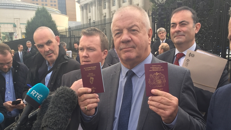 Campaigner Raymond McCord poses outside the court with his new Irish passport after the ruling