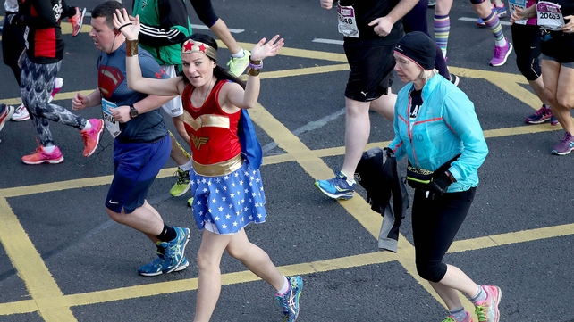 Wonderwoman waves to the crowd as Superman concentrates on the road
