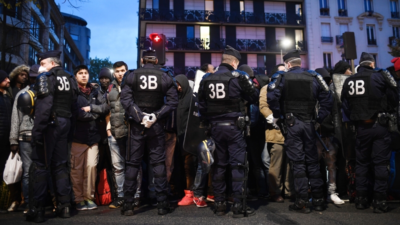 Police cordon migrants before they board a bus to leave the camp