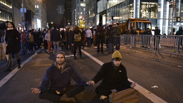Two people sit in the middle of 5th Avenue, New York, during a protest over Trump's election win