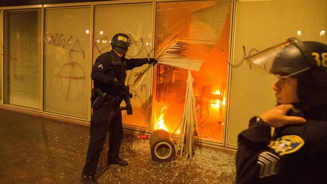 Police investigate a fire lit by protesters during an anti-Trump protest in Oakland, California