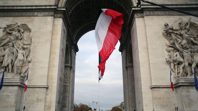 Soldiers stand next to the Tomb of the Unknown Soldier under a French national flag at the Arc de Triomphe in Paris