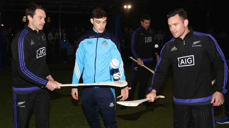 Ben Smith (L) and Ryan Crotty (R) try their hand at hurling under the guidance of Dublin's Eoghan O'Donnell at the AIG Skills Challenge