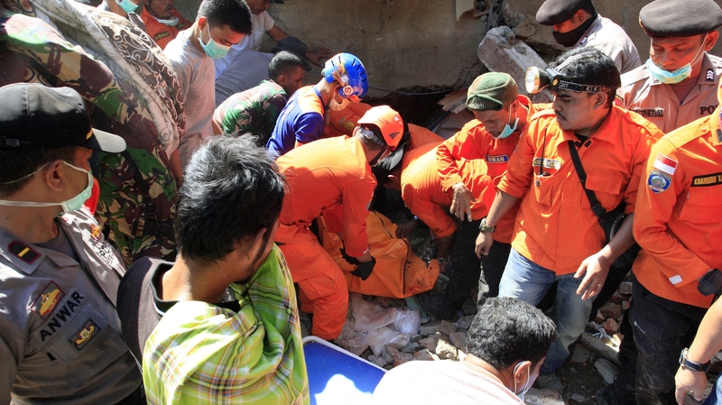 Indonesian rescue workers pull victims from destroyed buildings